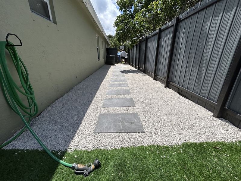 Completed side yard with white gravel, grey stepping pavers and turf edging